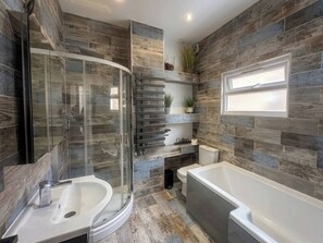 A modern bathroom with a glass shower enclosure, a freestanding bathtub, and a built-in toilet. - Charming 2-Bed Ground Floor Apartment in Central London (London)