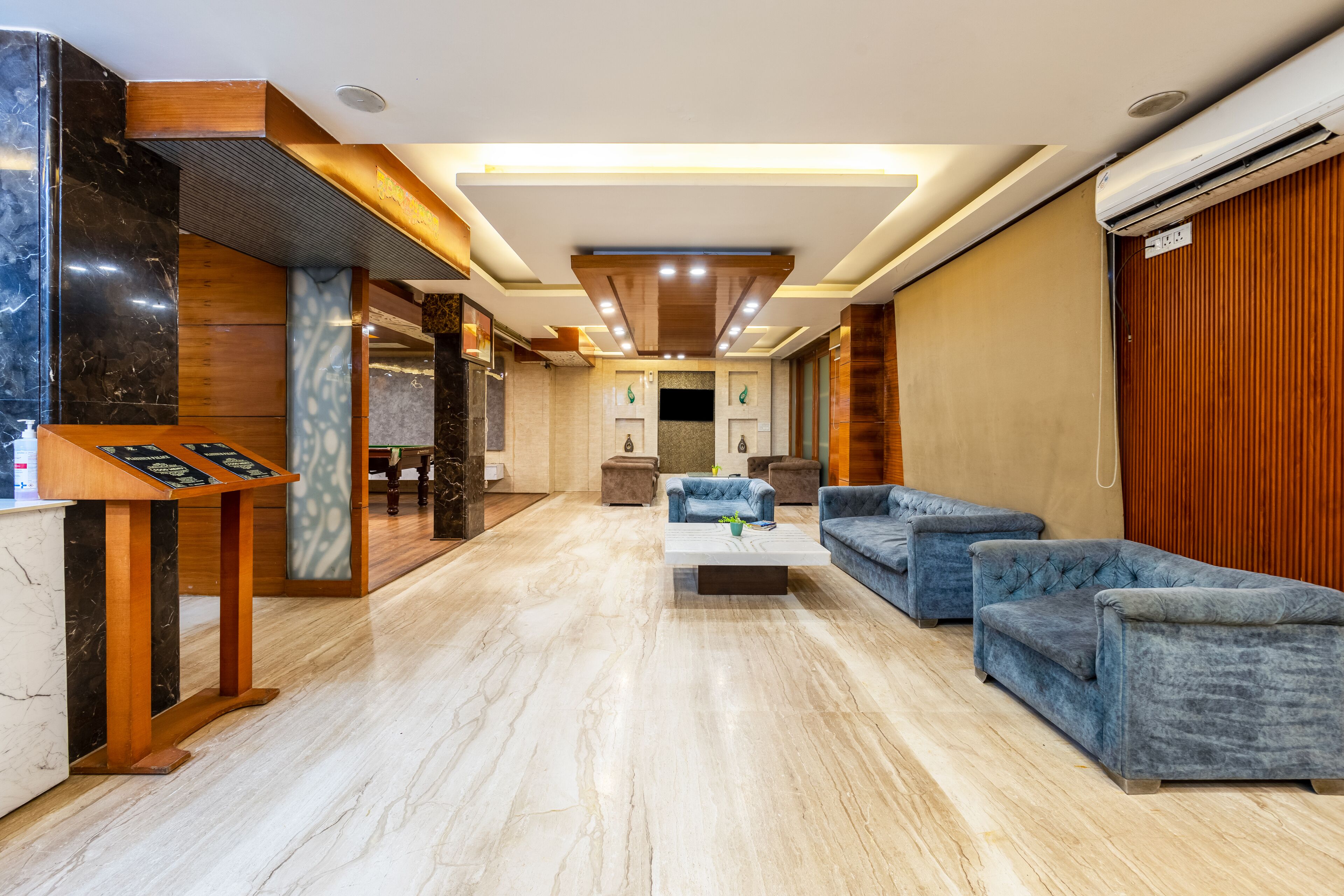 Um hall de hotel moderno com piso de mármore, balcão de recepção e sofás estofados em azul.