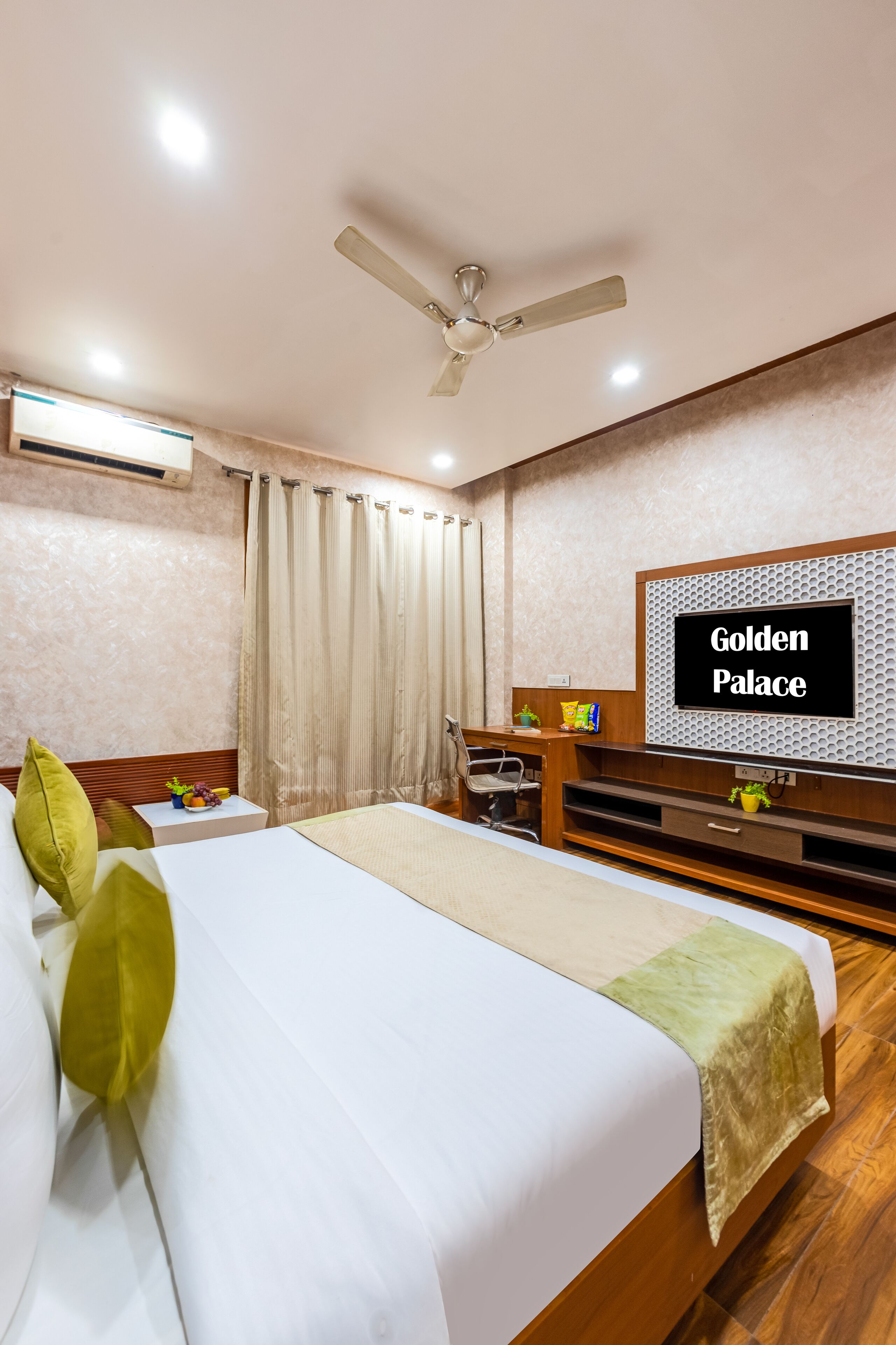 A hotel room with a bed, a desk, a television, and a ceiling fan.