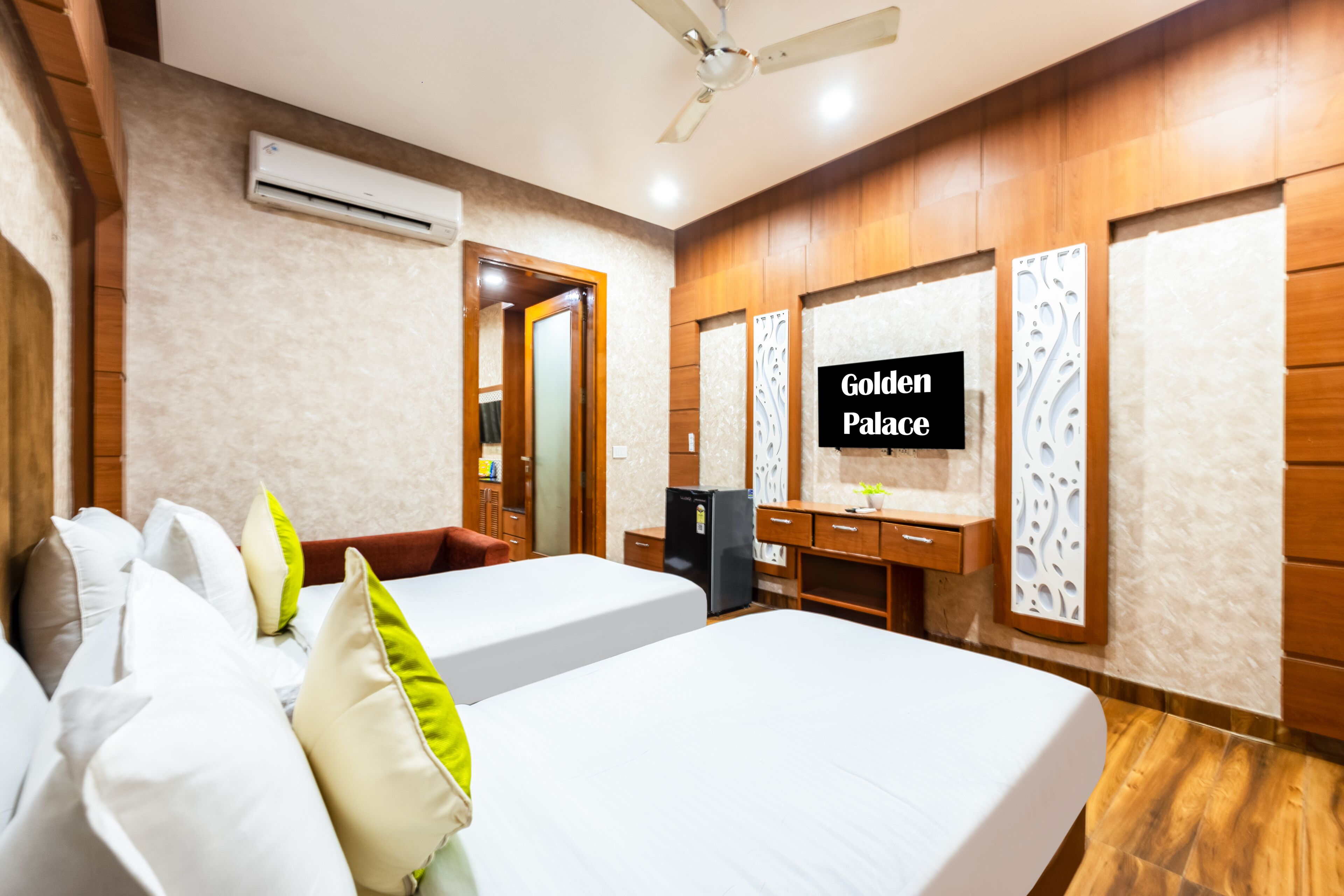 A hotel room with two beds, a desk, a refrigerator, and a mirror.