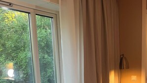 Una stanza con un'ampia finestra, un termosifone, una panca e una lampada.