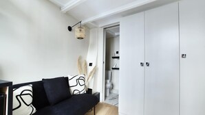 Ein modernes Wohnzimmer mit einer schwarzen Couch, einem weißen Kleiderschrank und einer Pendelleuchte.