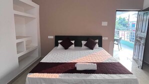 Ein Schlafzimmer mit einem Bett, einer weißen Wandverkleidung, einem gemusterten Teppich und Blick ins Freie.