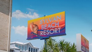 En stor reklamskylt för Sylvan Beach Resort, där man tydligt kan se resortens namn och en del av byggnaden.