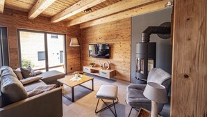 Een moderne woonkamer met een houten plafond, een flatscreen televisie, een open haard en een bank.