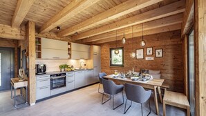 A modern kitchen with wooden beams, a dining area with a wooden table and chairs, and a large window.