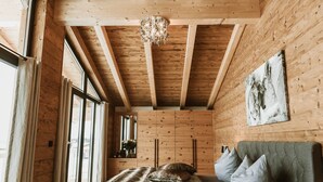 A wooden interior with a bed, a sofa, and a chandelier.