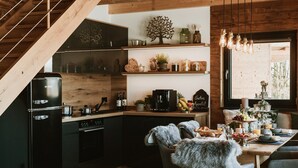 A cozy kitchen with a wooden staircase, a coffee machine, and a breakfast setup on the dining table.