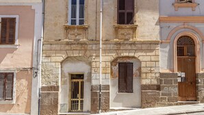 A historic building with stone facade, multiple windows with shutters, and a central arched doorway. - Carlo's Apartment | Near the train and bus station | 2 minutes from the city center | Free Netflix and Wi-Fi (Sassari)