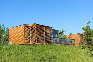 A modern wooden cabin with a slatted exterior, a balcony, and a clear sky. - Familienfreundliches MobileHome im Vital Camp Bayerbach (Bayerbach)