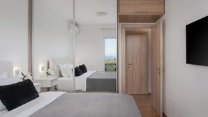 Ein modernes Schlafzimmer mit einem großen Bett, Nachttischen, einem Kleiderschrank und einem Fernseher.