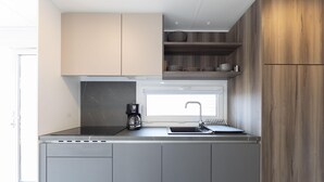 Una cucina compatta con piano cottura integrato, una macchina per il caffè e una finestra sopra il lavello.