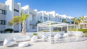 A rooftop terrace with white modern architecture, outdoor seating, and a pergola structure. - Pure South apartment 11.2a (Manilva)