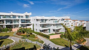 A modern multi-story hotel with balconies, outdoor seating, and a landscaped garden. - Pure South apartment 11.2a (Manilva)