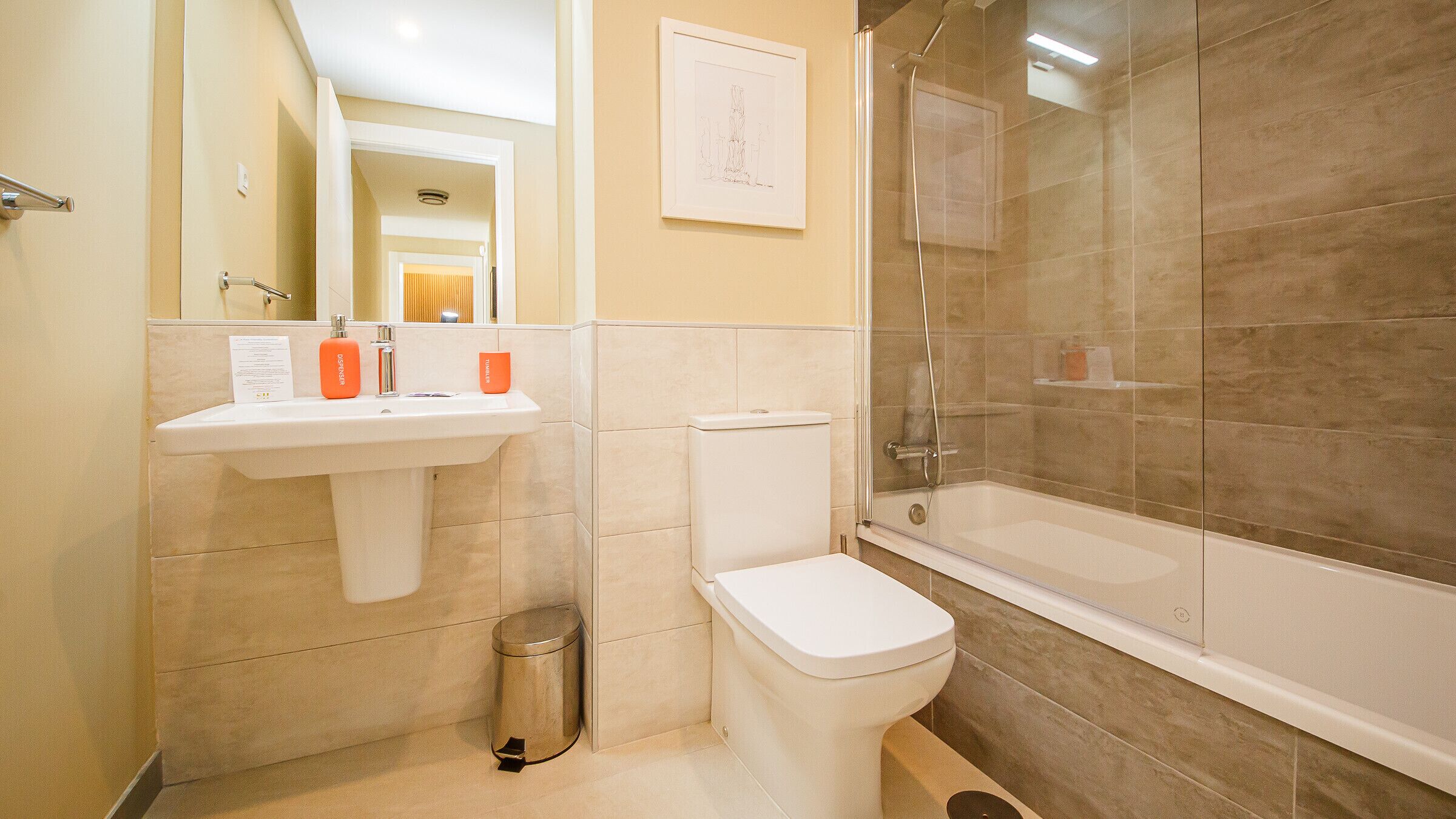Une salle de bain moderne équipée de toilettes, d’un lavabo et d’une douche à parois de verre.