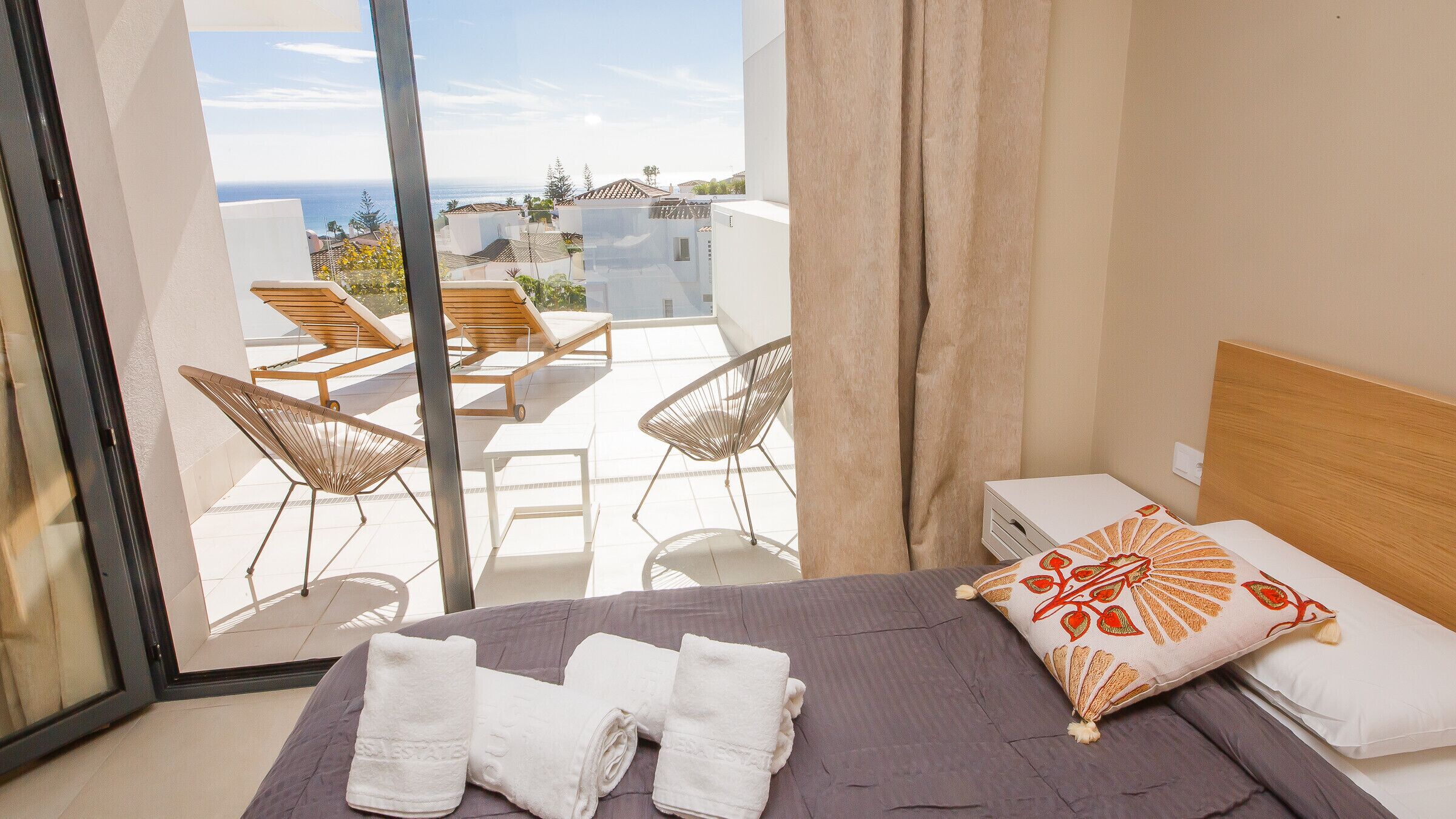 Ein Hotelzimmer mit Bett, Meerblick und einem Balkon mit Stühlen und einem Tisch.