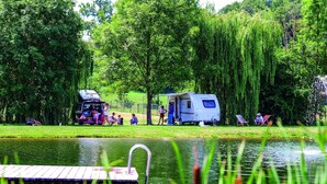 A camping area with a trailer, a dock, and a pond.