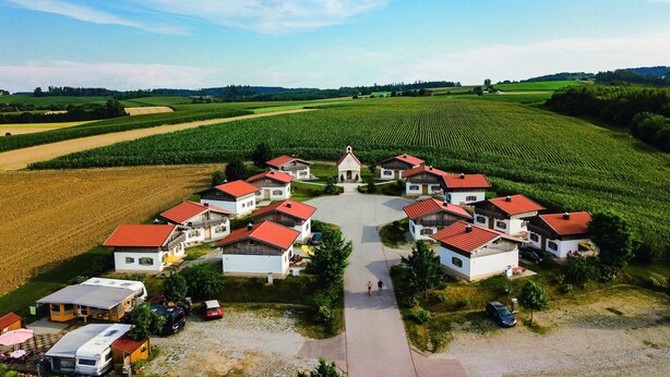 A rural village with houses, a central building, and surrounding fields.