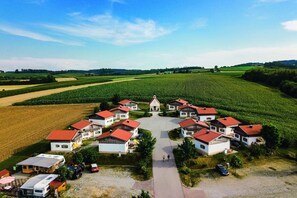 Un village rural avec des maisons, un bâtiment central et des champs environnants.