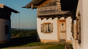 Ein traditionelles Gebäude mit einem hölzernen Balkon, einer Holztür und Blick auf die Landschaft.