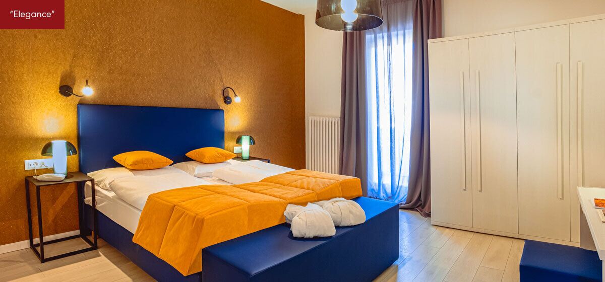Ein Schlafzimmer mit einem großen Bett, zwei Nachttischen, einem Kleiderschrank und einem Fenster mit Vorhängen.