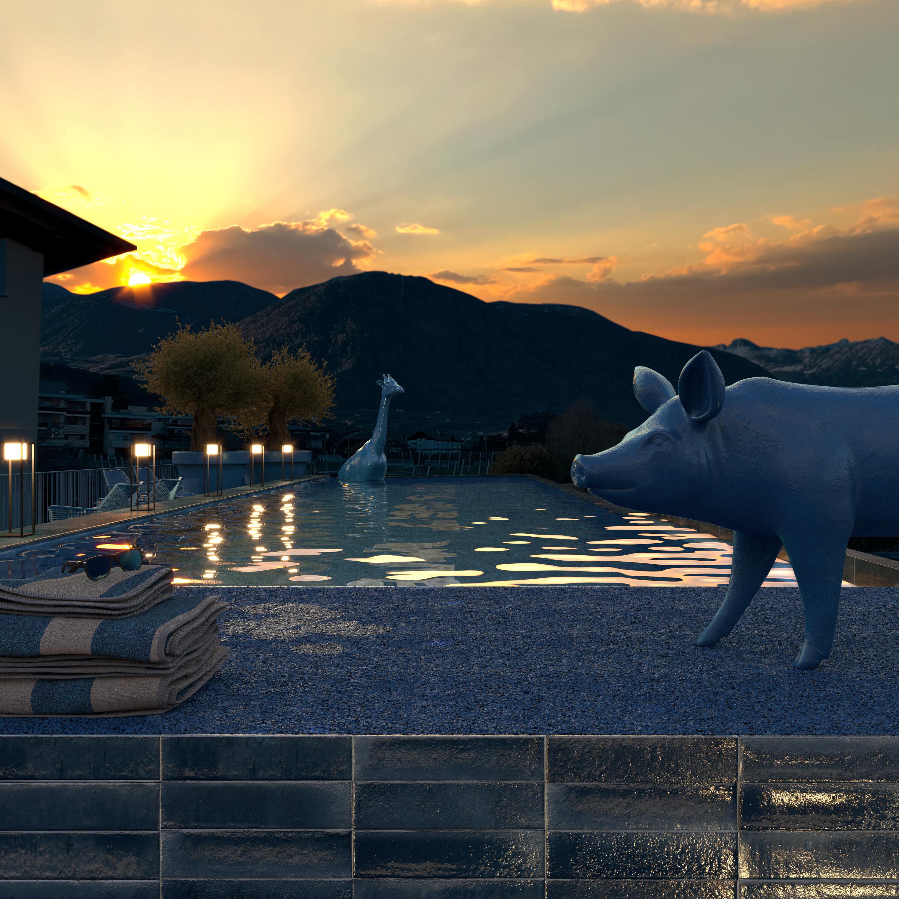 A pool with a giraffe and a pig statue, surrounded by buildings and mountains in the background.