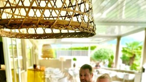 A family dining at a table with a wicker overhead canopy, surrounded by greenery and outdoor seating. - SCHLOSSHOF SÜDTIROL – Hotel & Camping Resort (Lana)