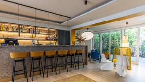 A modern bar area with a marble countertop, multiple stools, and a variety of bottles and glasses. - SCHLOSSHOF SÜDTIROL – Hotel & Camping Resort (Lana)