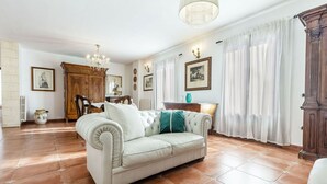 Una sala de estar con un sofá de color claro, un mueble de madera y una araña.