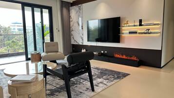 Una sala de estar moderna con televisor de pantalla plana, asientos, chimenea y vistas al exterior.
