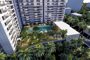 Un edificio de gran altura con piscina en la azotea y zonas verdes circundantes.