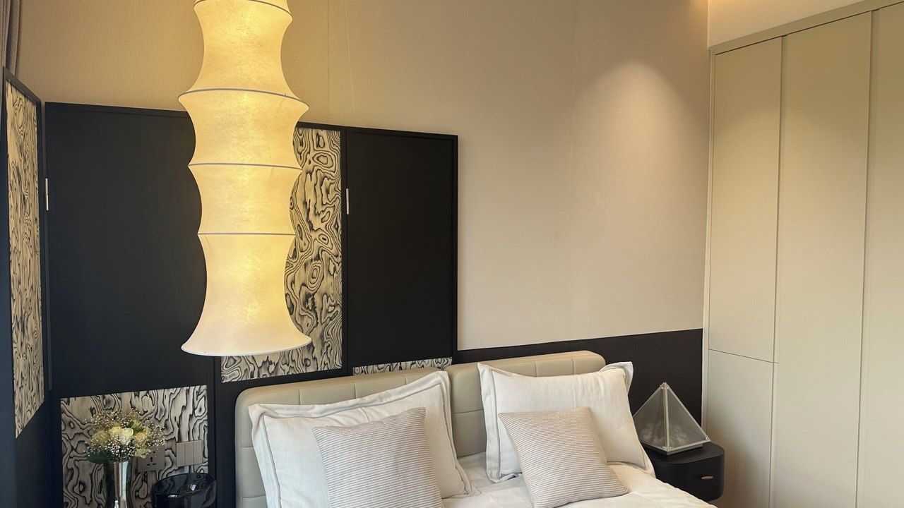 Habitación de hotel moderna con una cama grande, una mesita de noche, un panel decorativo en la pared y una lámpara colgante original.