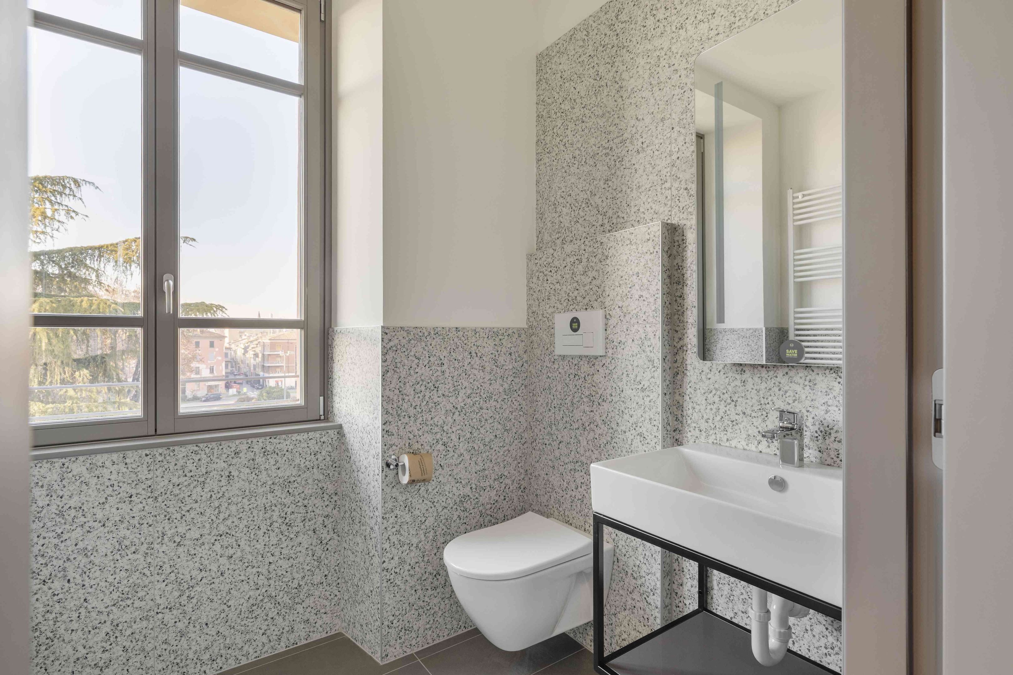 A bathroom with a toilet, sink, and large window.