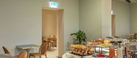 A breakfast buffet with various food items and a plant in the background.