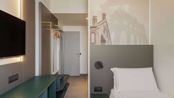 A hotel room with a bed, a TV, a desk, and a wardrobe.