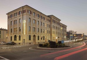 Un hotel de varios pisos con un diseño arquitectónico clásico, que presenta ventanas en arco y una entrada central.