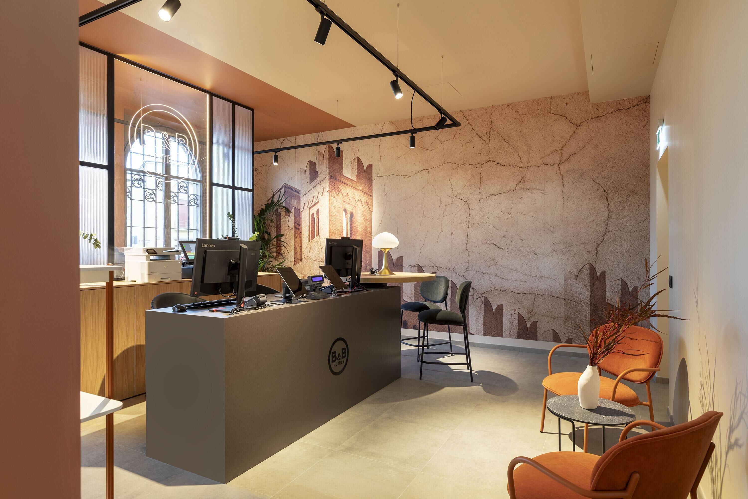 A reception area with a desk, chairs, a plant, and a mural on the wall.