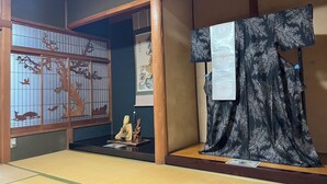 A traditional Japanese room with tatami flooring, a shoji screen, a hanging scroll, and a statue.