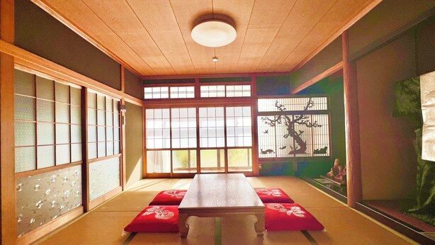 A traditional Japanese room with tatami flooring, a low wooden table, and sliding doors with glass panels.