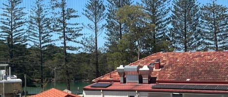 Un immeuble résidentiel avec un toit recouvert de tuiles rouges, des panneaux solaires et une vue sur de grands arbres.
