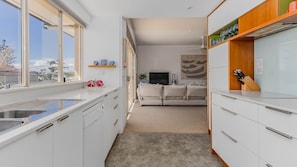 A modern kitchen with white cabinets, a built-in oven, and a large window.