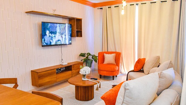 Una sala de estar con una mesa de centro de madera, un sillón naranja y un sofá blanco.
