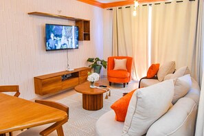 Een woonkamer met een houten salontafel, een oranje fauteuil en een witte bank.