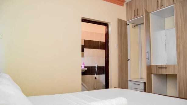 Habitación de hotel con cama, armario y baño visible a través de una puerta abierta.