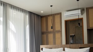 Ein modernes Hotelzimmer mit einem großen Bett, einem Holz-Kopfteil und einer eingebauten Klimaanlage.