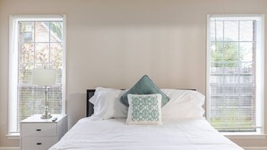 Un dormitorio con una cama, dos mesitas de noche y una ventana con persianas.