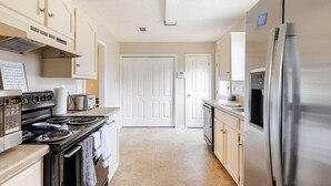 Una cocina moderna con electrodomésticos de acero inoxidable, armarios color beige y una distribución limpia y ordenada.