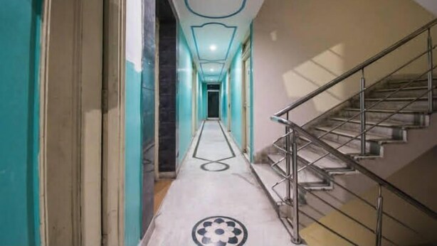 A hallway with a staircase on the right, a patterned floor, and a ceiling with a geometric design. - HOTEL MUNDRIKA DELUXE (Patna)