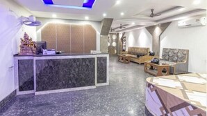 A hotel reception area with a marble counter, a sofa, and a patterned bed. - HOTEL MUNDRIKA DELUXE (Patna)