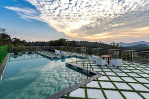 Una piscina con vistas a montañas y al atardecer.